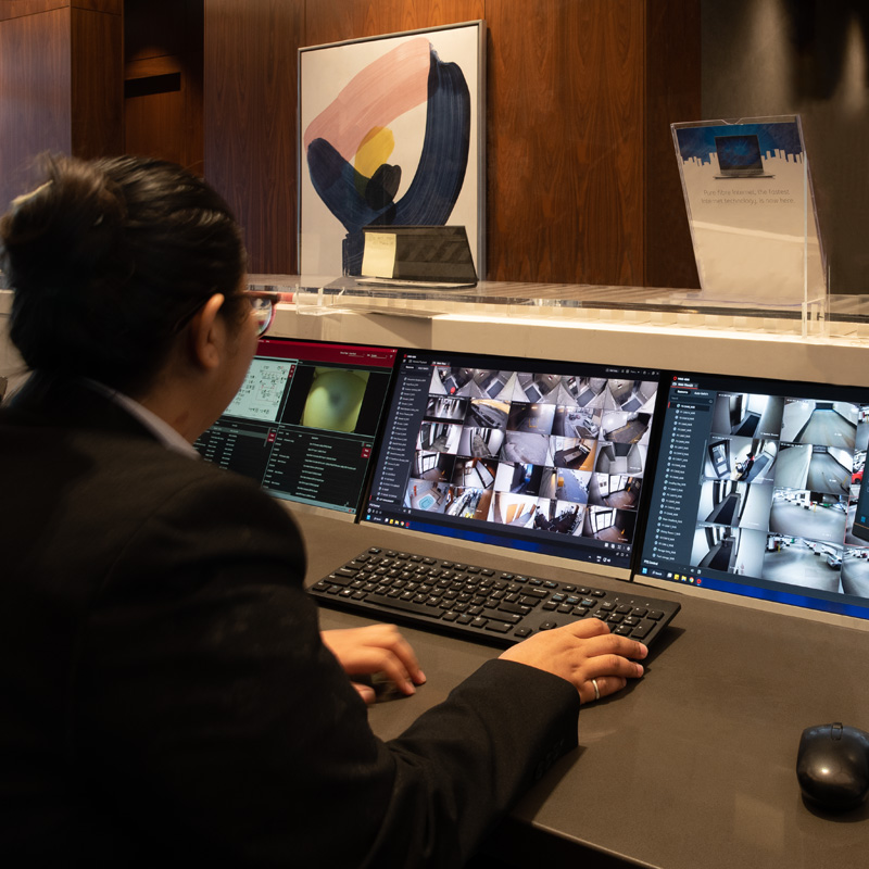 A concierge sitting behind a desk watching security screens